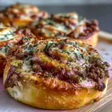 Sliced Irresistible High Protein Pepperoni Pizza Rolls reveal pepperoni and lean beef filling on a marble counter.