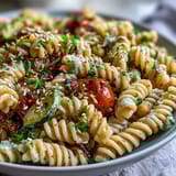 Garnished chickpea pasta bowl with parsley and sesame seeds, served warm for a nourishing plant-based dinner.