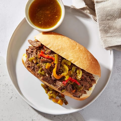 Italian Beef Sandwich recipe served open-faced with a side of rich dipping au jus and pickled vegetables.