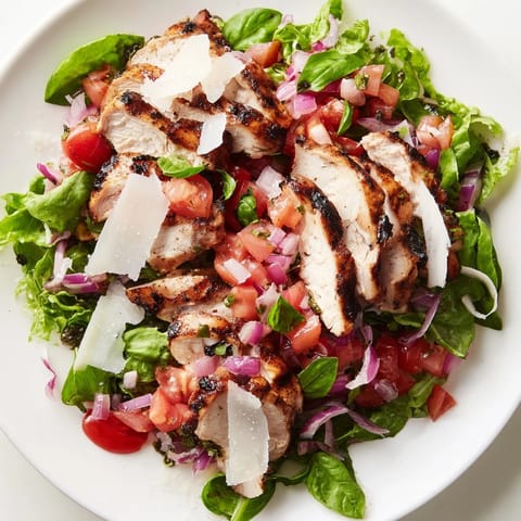 Freshly grilled chicken breasts and ripe diced tomatoes for Bruschetta Chicken Salad resting beside a bowl of zesty balsamic dressing and crisp greens.  