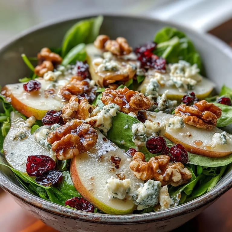 Vibrant pear Gorgonzola salad with toasted walnuts and dried cranberries, served as a light vegetarian meal.