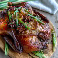 A beautifully roasted Five-Spice Roast Duck with crispy, golden-brown skin, served beside fluffy jasmine rice and vibrant stir-fried greens.